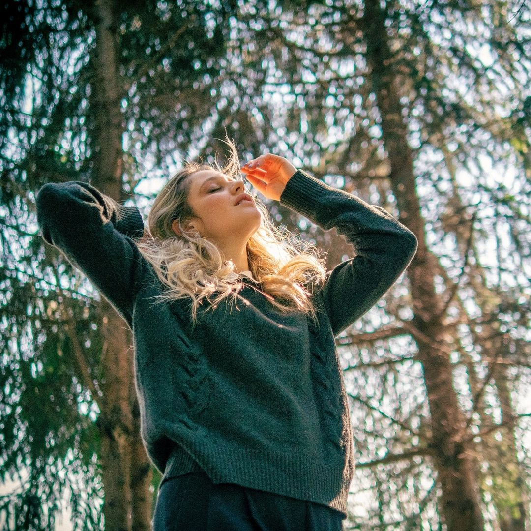 a woman holding a bottle of orange juice in a forest